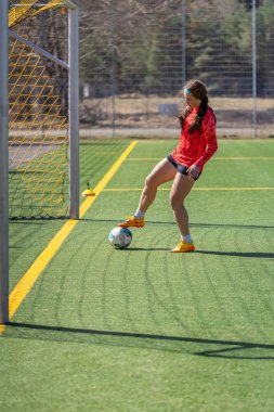 Futbol sahasındaki kız. Futbol antrenmanı. Aktif yaşam tarzı. Futbol konsepti. Yüksek kalite fotoğraf. Futbol formalı bir kız futbol topuyla oynuyor..