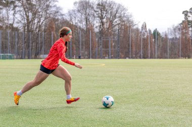 Futbol sahasındaki kız. Futbol antrenmanı. Aktif yaşam tarzı. Futbol konsepti. Yüksek kalite fotoğraf. Futbol formalı, futbol topuyla oynayan sporcu bir kız. Metin için boşluk.