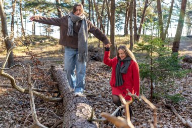 Ormanda yürüyen iki kadın. Orman. Doğa. Açık hava eğlencesi. Yüksek kalite fotoğraf. Soğuk hava. Doğa gezisi. Düşen ağaç gövdesinden geçen bir kadın..