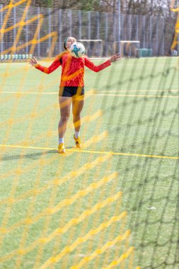 Futbol sahasındaki kız. Futbol antrenmanı. Aktif yaşam tarzı. Futbol konsepti. Yüksek kalite fotoğraf. Futbol formalı, futbol topuyla oynayan sporcu bir kız. Metin için boşluk.