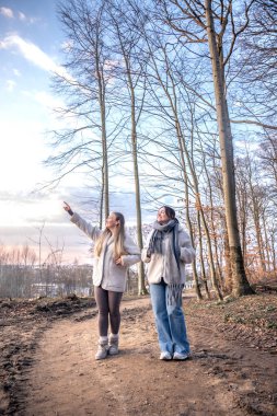 Ormanda iki kadın. Manzarayı gösteren bir kadın. Doğadaki insanlar. Yüksek kalite fotoğraf. Ormanda bir yürüyüş, doğada. Bahar, sonbahar mevsimi.