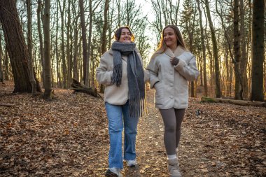 Ormanda yürüyüş yapan iki bayan arkadaş. Ormanda yürüyen arkadaşlar. Doğadaki insanlar. Yüksek kalite fotoğraf. Ormanda bir yürüyüş. Doğada rahatlama.