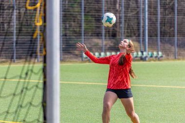 Futbol sahasındaki kız. Futbol antrenmanı. Aktif yaşam tarzı. Futbol konsepti. Yüksek kalite fotoğraf. Futbol formalı bir kız futbol topuyla oynuyor..