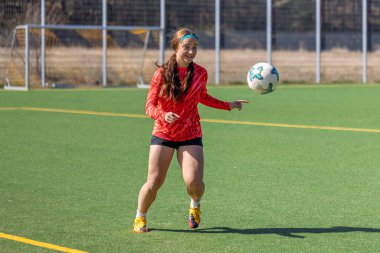 Futbol sahasındaki kız. Futbol antrenmanı. Aktif yaşam tarzı. Futbol konsepti. Yüksek kalite fotoğraf. Futbol formalı bir kız futbol topuyla oynuyor..
