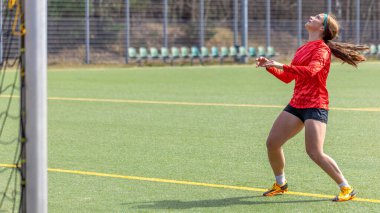 Futbol sahasındaki kız. Futbol antrenmanı. Aktif yaşam tarzı. Futbol konsepti. Yüksek kalite fotoğraf. Mesaj için yer var. Futbol formalı bir kız futbol topuyla oynuyor..