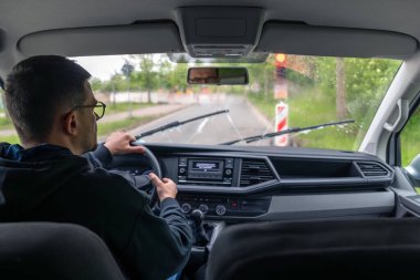 Adam yağmurlu havada ön camları sileceklerle temizliyor..