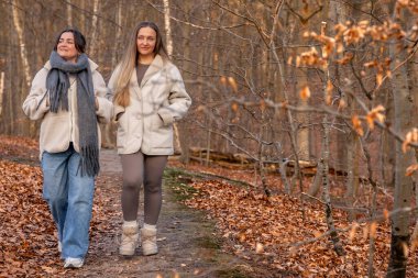 Ormanda yürüyen iki kadın. Orman. Doğa. Açık hava eğlencesi. Yüksek kalite fotoğraf. Ormanda bir patika boyunca yürüyen iki kadın. Soğuk hava. Metin için boşluk.