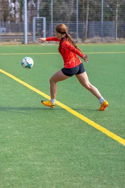 Futbol sahasındaki kız. Futbol antrenmanı. Aktif yaşam tarzı. Futbol konsepti. Yüksek kalite fotoğraf. Futbol formalı bir kız futbol topuyla oynuyor..