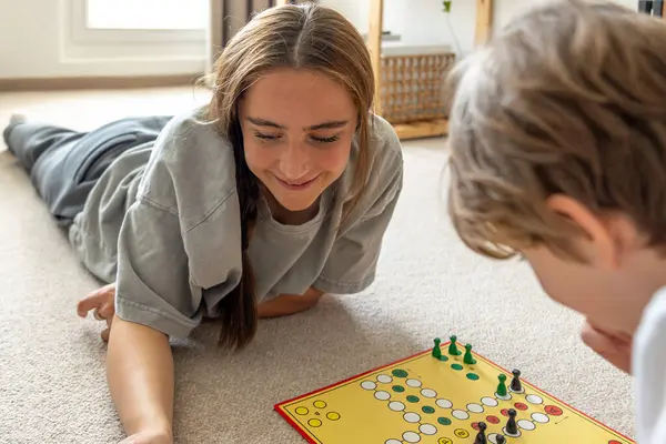 Küçük kardeşle masa oyunu oynayan bir kız. Masa oyunu. Yüksek kalite fotoğraf. Genç kız kardeşiyle masa oyunu oynuyor. Eğitim tahtası oyunu.