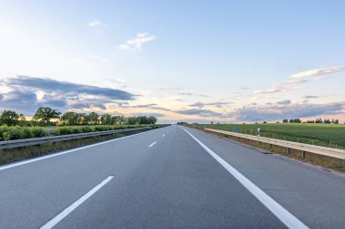 Gece gökyüzünün altındaki rüzgâr tarlasına giden düz bir yol. Önümüzde yeşil bir altyapı var..