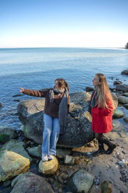 Deniz kıyısında yürüyen iki kadın. İki arkadaş eğleniyor ve birlikte vakit geçiriyorlar. Yüksek kalite fotoğraf. Doğada bir yürüyüş. Boşluğu kopyala.