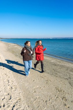 Deniz kıyısında yürüyen iki kadın. İki arkadaş eğleniyor ve birlikte vakit geçiriyorlar. Yüksek kalite fotoğraf. Doğada bir yürüyüş. Deniz. Deniz kıyısında koşuyor..