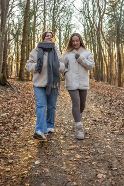 Ormanda yürüyüş yapan iki bayan arkadaş. Ormanda yürüyen arkadaşlar. Doğadaki insanlar. Yüksek kalite fotoğraf. Ormanda bir yürüyüş. Doğada rahatlama.