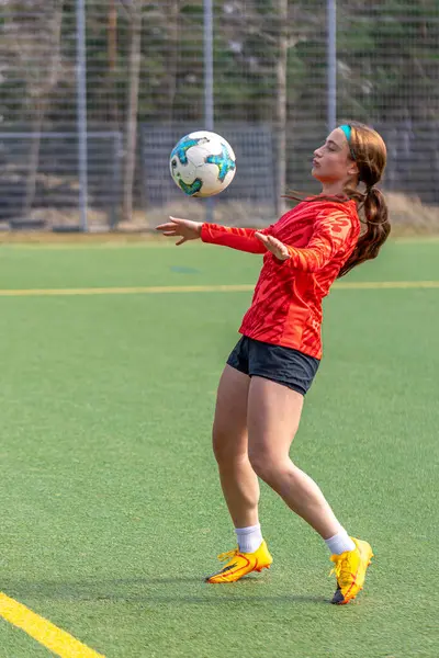 Futbol sahasındaki kız. Futbol antrenmanı. Aktif yaşam tarzı. Futbol konsepti. Yüksek kalite fotoğraf. Futbol formalı bir kız futbol topuyla oynuyor..