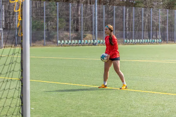Futbol sahasındaki kız. Futbol antrenmanı. Aktif yaşam tarzı. Futbol konsepti. Yüksek kalite fotoğraf. Futbol formalı bir kız futbol topuyla oynuyor..