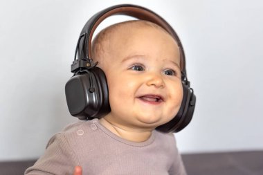 Kulaklıklı neşeli bir bebek neşeli bir şekilde gülümser, rahat ve neşeli bir ortamda müzikten zevk alır..