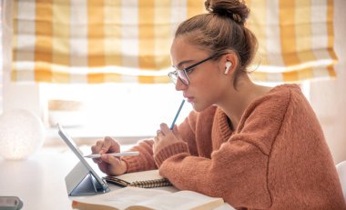 Bir kız öğrenci evde telefonla konuşuyordu. Telefondaki konuşmalar. Yüksek kalite fotoğraf. Gözlüklü kız.