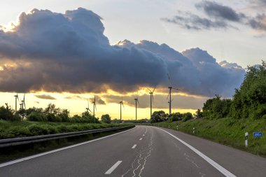 Bir grup modern yel değirmeni açık kırsal alanda akşam gökyüzü altında.