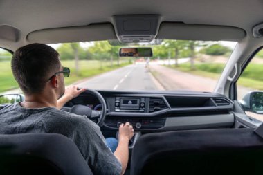 Direksiyonda odaklanmış bir adamla şehrin içinden geçen bir arabanın iç görüntüsü..