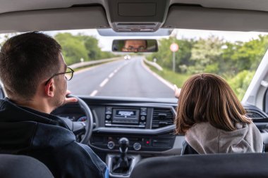 Sürücü bahar ormanı yolunda seyahat ederken elini ileri doğru uzatır. Arabanın içindeki güven ve kurnazlığı yakaladığımız an..
