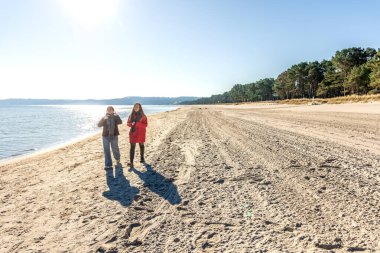Deniz kıyısında yürüyen iki kadın. İki arkadaş eğleniyor ve birlikte vakit geçiriyorlar. Yüksek kalite fotoğraf. Doğada bir yürüyüş. Uzayı kopyala Soğuk hava.