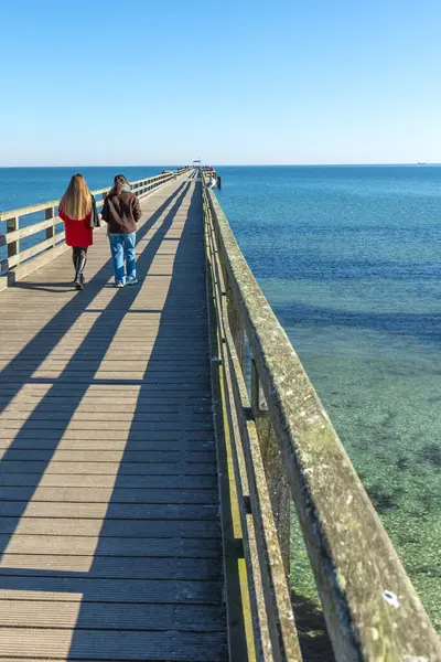 İskelede iki kadın. İskelede yürüyen iki kadının arka görüntüsü. Yüksek kalite fotoğraf. Deniz. Mesaj için yer var. Gezinti güvertesinde yürü.