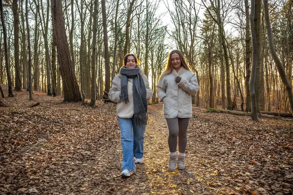 Ormanda yürüyüş yapan iki bayan arkadaş. Ormanda yürüyen arkadaşlar. Doğadaki insanlar. Yüksek kalite fotoğraf. Ormanda bir yürüyüş. Doğada rahatlama.