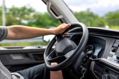 Sürücülerin yakın çekimde direksiyonun tepesine çıkmaları. İç mekan rahat ve gerçekçi bir sürüş anı yakalıyor..