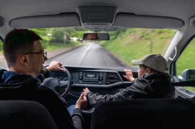 Erkek sürücü ve kadın yolcu, yağmurlu bir yolculukta orman yolunda yanındalar. Arabanın içinden görünüm seyahat ve bağlantıyı vurgular.