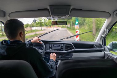 Şoför yağmurda kırmızı ışıkta bekliyor. Islak şehir caddesinde bir araba geçerken..