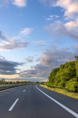 Mobil kulesi olan düz asfalt karayolu ve her iki tarafında bulutlu akşam gökyüzü..