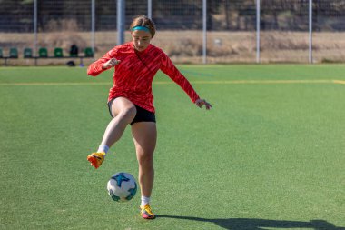Futbol sahasındaki kız. Futbol antrenmanı. Aktif yaşam tarzı. Futbol konsepti. Yüksek kalite fotoğraf. Futbol formalı bir kız futbol topuyla oynuyor..