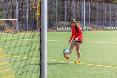 Futbol sahasındaki kız. Futbol antrenmanı. Aktif yaşam tarzı. Futbol konsepti. Yüksek kalite fotoğraf. Futbol formalı bir kız futbol topuyla oynuyor..