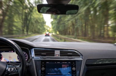 Ormanlık bir yolda ilerleyen bir arabanın içinden gösterge panelinde GPS ve medya oynatıcısı ile görüntüyü görüntüle.