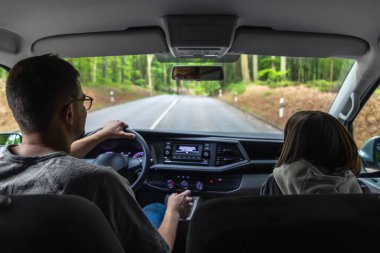 Orman yolundan geçen yolcu koltuğunda çocukla araba süren bir adamın iç çekimi..