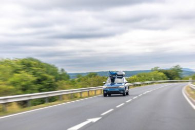 Çatı rafı boş bir yolda hız, seyahat ve özgürlüğü vurgulayan dinamik hareket bulanıklığı olan modern bir SUV..
