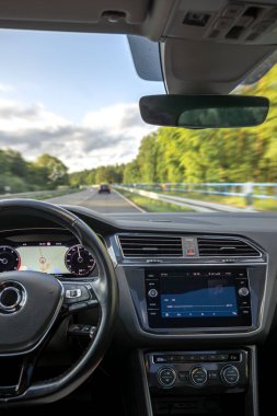 İç sürüş perspektifi ekranda bir GPS rotası ve müzik kaydı gösterirken, yeşil manzaralı doğada seyahat ederken.