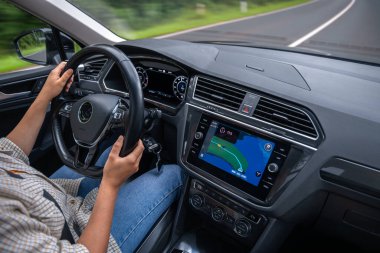 Bir kadın, modern bir arabanın direksiyonunu tutarak otoyolda aktif navigasyonla geziyor. Hareket halinde biçim ve konfor.