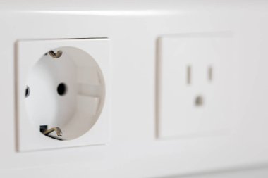 Makrodaki temiz beyaz Euro prizinin yanında hafif bulanık ABD prizi akıllı bir ev için parlak bir güvenlik titreşimi var..