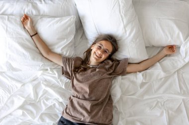 Gözlüklü, kollarını beyaz yastıklara açmış gülümseyen bir kız. Özgürlüğünü, rahatlığını ve şık bir yaşam tarzını ifade ediyor..