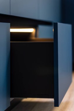 Bir LED şeridi, çekmece açılırken keskin bir köşegen çizer. Dar mahsul, kalın kontrast ve mat renkleri grafiksel, çağdaş bir titreşim verir.