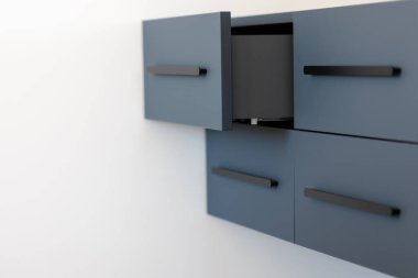 Uzun siyah çekişleri olan, duvara monte edilmiş mavi bir dolabın geniş açılı görüntüsü, üst çekmece açık. Beyaz duvarda geniş negatif alan temiz çizgiler ve havadar Scandic minimalizmi vurguluyor.