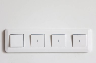 Beyaz bir duvarda dört ışık düğmesi olan panel. Basit geometri ve düzenli kenarlar modern ışıklandırma denetimini vurguluyor.