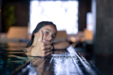 Havuz kenarındaki baş parmağın yakın görüntüsü. Kız hafifçe odak noktasından çıkmış. Gün ışığı ve parlak fayanslar gevşemiş bir sağlık havası yaratır..