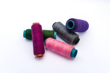 İzole edilmiş beyaz arka plana renkli dikiş iplikleri yığını. Giysi endüstrisinde fabrikaların kullandığı renkli iplikler..