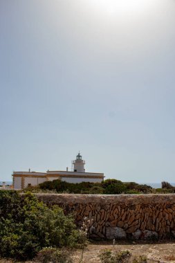 Dağın tepesine tünemiş el değmemiş beyaz bir deniz feneri, berrak mavi bir deniz manzaralı. Beyaz yapı ve canlı mavi sular arasındaki çarpıcı zıtlık dingin bir güzellik manzarası yaratır. Seyahatle ilgili konular için ideal