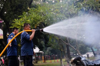 Jakarta, Endonezya. 21 Nisan 2024. TMII, Jakarta: İtfaiyeciler yanmış bir Ogoh-ogoh 'un üzerindeki alevleri söndürüyor