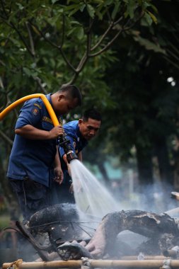Jakarta, Endonezya. 21 Nisan 2024. İtfaiyeciler, TMII turistik merkezinde Ogoh-ogoh 'u yakan yangını söndürmek için yüksek basınçlı su püskürtüyorlar, Jakarta..