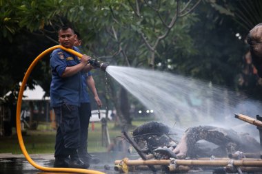Jakarta, Endonezya. 21 Nisan 2024. İtfaiyeciler, TMII turistik merkezinde Ogoh-ogoh 'u yakan yangını söndürmek için yüksek basınçlı su püskürtüyorlar, Jakarta..