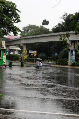 Jakarta, Endonezya. 27 Haziran 2024. Fotoğraf, TMII turist merkezinde şiddetli yağmur yağdığını gösteriyor, Jakarta. Şemsiyeler ve yağmurluklar giyilir..